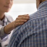 Pflegerin oder Ärztin, die einen kranken Mann mitfühlend berät und an der Schulter berührt ©fizkes/Shutterstock.com