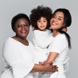 Junge afrikanische-amerikanische Frau mit Mutter und Tochter, lächelnd und sich gegenseitig umarmend ©LightField Studios/Shutterstock.com 