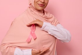 View of a Muslim woman in hijab with pink breast cancer ribbon at chest level ©Taras Grebinets/Shutterstock.com